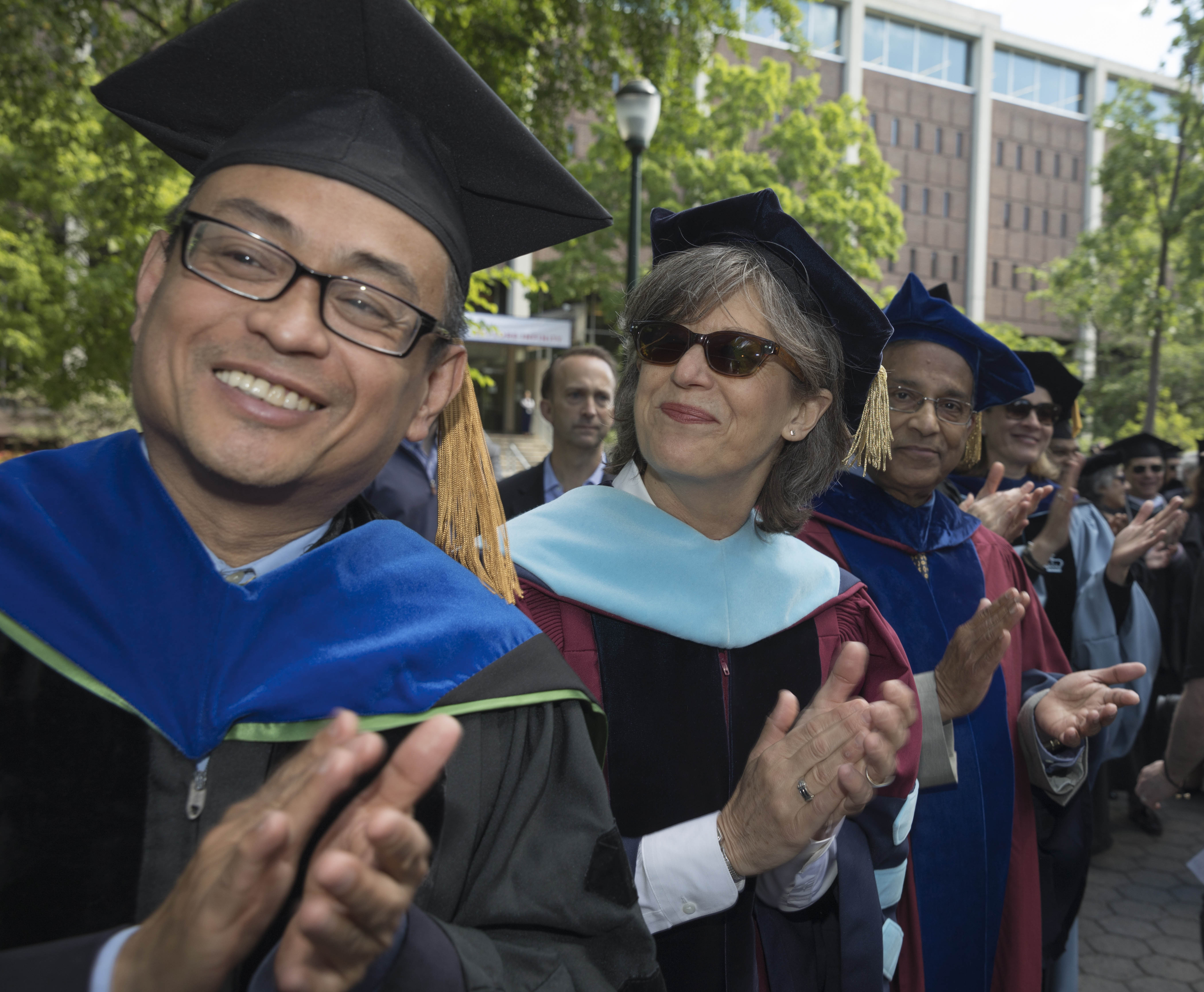 faculty in regalia clapping as graduates process