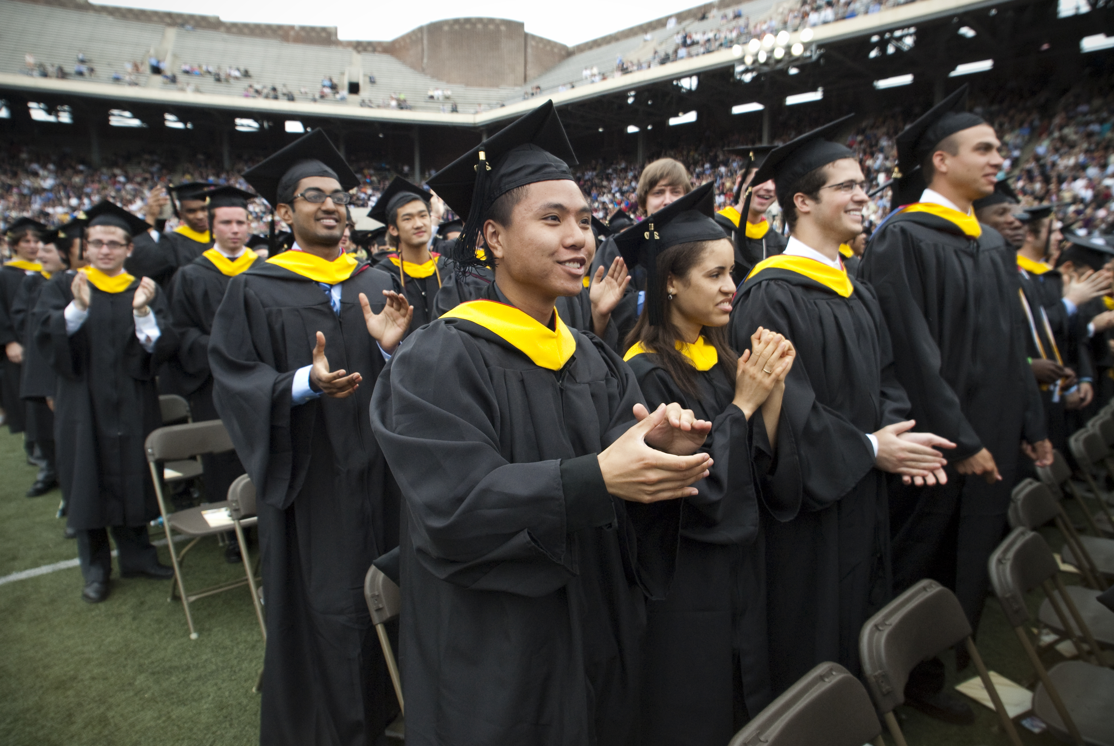 rows of grads standing and clapping on franklin field