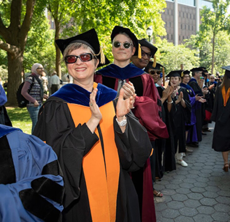 faculty clapping for graduates in procession